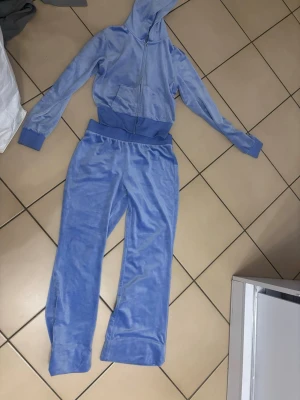 Blå mjukisbyxor i velour - Säljer ett par blå mjukisbyxor i mjuk velour med bred resår i midjan. Byxorna har en relaxed passform och är perfekta för chill dagar. Färgen är ljusblå och materialet känns riktigt skönt mot huden.