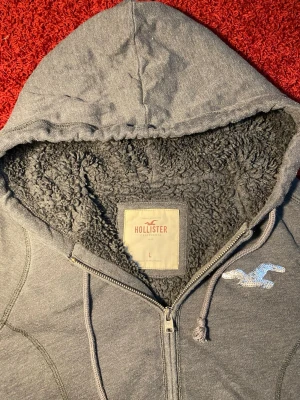 Hollister fodrad zip up hoodie - Hollister fodrad zip hoodie i storlek L. Mått: axelbredd - 38 cm, armhåla till armhåla - 50 cm, längd - 58 cm. Skriv för fler bilder och frågor!