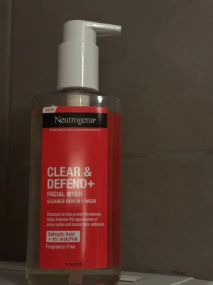 Neutrogena Clear & Defend+ ansiktsrengöring - Ansiktsrengöring från Neutrogena med pumpflaska, röd etikett och transparent plast. Innehåller salicylsyra och 4% AHA/PHA, parfymfri. Utvecklad för att motverka finnar och ge klarare hud på en vecka. Helt oanvänd. 