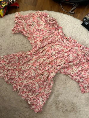 Blommig rosa tröja  med volang - Superfin tröja med blommigt mönster i rosa och vitt.  och hals, samt smockad midja för en skön passform. Perfekt för varma dagar och har en lätt, flowy känsla. Materialet känns som tunn polyester.