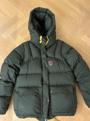 Fjällräven expedition down lite jacket W- storlek M - Säljer en Expedition Down Lite Jacket W i färgen deep forest från Fjällräven. Jackan ger mycket bra isolering och har detaljer som rejäl dunfylld huva, justerbara snoddar och rymliga fickor. Lätt figursydd för att ge en bra passform. Jackan är i mycket gott skick och har används mycket sparsamt. Kvitto finns. 