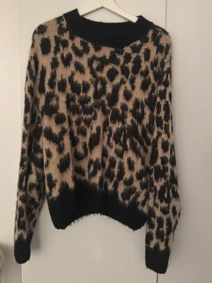 Leopardmönstrad stickad tröja Yu & Me - Säljer en stickad tröja från Yu & Me Paris i storlek S/M. Tröjan har ett snyggt leopardmönster i beige och svart, med ribbade muddar och rund hals. Perfekt för dig som gillar djurmönstrat och vill ha en mysig, trendig look.