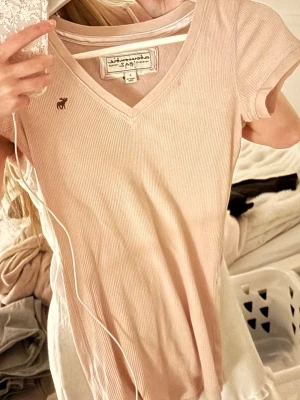 Y2k tshirt - Ljusrosa t shirt från Abercrombie & Fotch i stl L, passar som en S. Den har sin ikoniska logga i brunt. 