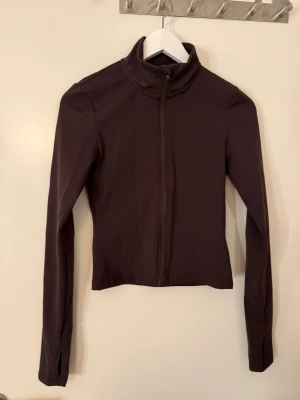 brun träningsjacka H&M Move - Sportig brun träningsjacka från H&M Move i storlek XS. Jackan har dragkedja framtill, hög krage och långa ärmar med tumhål. Materialet är mjukt och stretchigt, perfekt för träning eller aktiva dagar. Enkel och stilren design som funkar till allt.