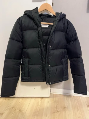  pufferjacka från Calvin Klein Jeans - Svart pufferjacka från Calvin Klein Jeans. Använd ett fåtal gånger och hängt i garderoben ett bra tag nu. Då den knappt är använd har den perfekt volym kvar och ser nästan ny ut. 