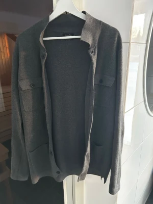 Mörkgrå overshirt från Massimo Dutti - Snygg mörkgrå overshirt från Massimo Dutti i extrafin bomull. Jackan har två bröstfickor med knappar och en stilren, rak passform. Perfekt att slänga på över en t-shirt för en chill look. Långärmad och enkel design. Hör av dig för frågor eller funderingar!