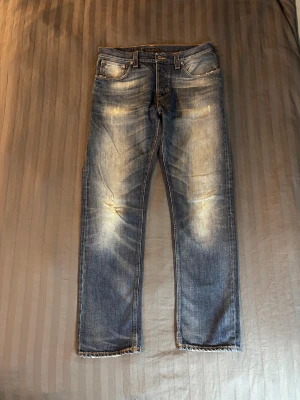 Nudie jeans big bengt - Tjena säljer ett par nudie jeans i modellen big bengt som som sitter åt relaxed straight-baggy hållet. De har en sjukt snygg wash som kommit från år av användning. De har också lite skön distress på som man kan se på de sista tre bilderna. Storleken är W33 L32. Undrar du något mer är det bara att höra av dig!