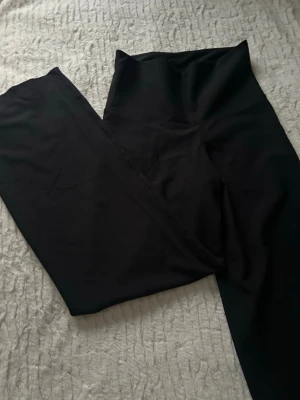 Svarta wide  byxor - Snygga svarta byxor med hög midja och wide fit. De har en stilren look och är tillverkade i ett mjukt, stretchigt material som sitter skönt. Perfekta för dig som gillar en trendig och avslappnad stil med raka ben och bekväm passform. Är uppsydda så passar en som är runt 157cm 