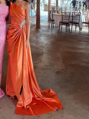 Bal/fest klänning  - Jätte snygg silkes orange fest klänning som är köpt i Nederländerna den är smal i midjan men har en fin slätt där bak den sticker upp lite på ena sidan och har en kristal på sidan av magen och har ett slit i benet passar både S,XS,XXS