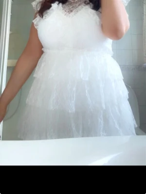 Vit spetsklänning med volanger - Säljer en vit kortklänning med flera lager volanger och spetsdetaljer vid halsen. Perfekt inför studenten den är använd men tvättad så den är helt kritvit och inga täcken på användning!🤍nypris 899kr