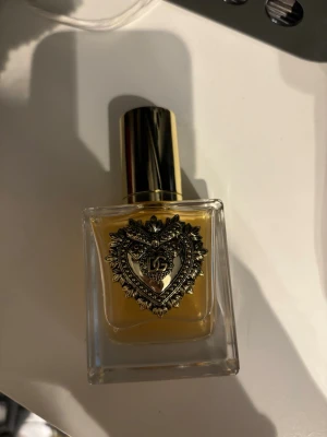 Dolce & Gabbana parfym - En exklusiv parfym från Dolce & Gabbana med en unik hjärtformad detalj på flaskan. Perfekt för dig som vill sticka ut och addera en lyxig touch till din stil.
