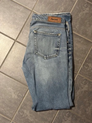 Blå raka jeans från Acne Studios - Säljer ett par klassiska blå jeans från Acne Studios med raka ben och normal passform. Ljus tvätt och subtila slitningar vid benslut. Perfekta till sneakers eller boots och tillverkade i mjukt bomullsjeans.