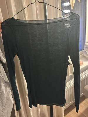 Mörkgrön tunn långärmad topp från intimissmi i storlek S - Säljer en mörkgrön, supertunn och genomskinlig långärmad topp med rund hals. Perfekt att styla lager på lager eller med ett snyggt linne under. Materialet känns lätt och luftigt, och toppen har en slim passform som sitter snyggt mot kroppen.