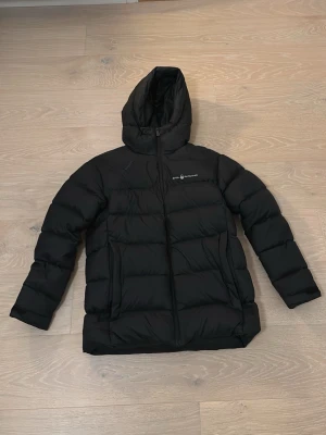 Svart pufferjacka från Sail Racing - Clean svart pufferjacka från Sail Racing. Jackan har ett litet sträck vid höger bröst men utöver de är jackan i väldigt bra skick. Jackan är i storlek 176. 