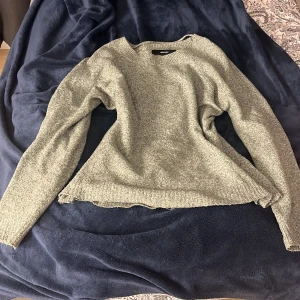 Grön stickad tröja från Vero Moda - Mysig grön stickad tröja från Vero Moda i storlek S. Tröjan har en klassisk rund halsringning och långa ärmar med ribbade muddar. Perfekt för lager-på-lager och chill dagar. Enkel och stilren design som funkar till det mesta.