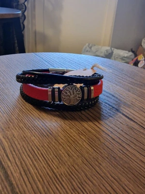 Armband livets träd - Armband livets träd i flätat konstläder med magnetlås. Röd. 21 cm lång. Bredd 3 cm.