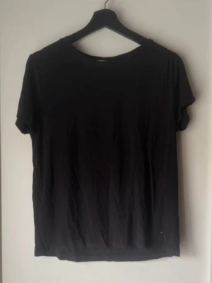 Svart basic t-shirt i bomull - Enkel svart t-shirt med rund hals och korta ärmar. Perfekt till jeans eller shorts och superlätt att matcha med andra plagg. Mjuk och skön bomull som andas. En klassiker i garderoben för en clean och avslappnad stil.