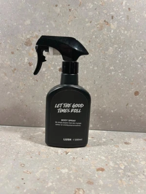 LUSH Let The Good Times Roll Body Spray - Säljer en LUSH Let The Good Times Roll body spray i svart plastflaska med spraymunstycke. Innehåller 200 ml och har en mysig doft av smörig popcornsötma. Perfekt för dig som gillar unika och söta dofter. Doftar vanilj 