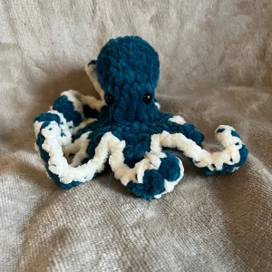 Virkad bläckfisk  - Söt liten virkad bläckfisk som passar perfekt som t.ex dekoration 🐙. Den är ca 11 cm hög.    VIKTIGT ‼️Färgen stämmer inte överens med bilderna, det faktiska färger är mer grönblå. Bläckfisken har Säkerhetsögon som inte rekommenderas för barn under 3 år så ha detta i åtanke vid köp! 