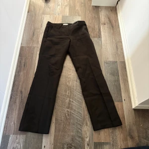 Svarta kostymbyxor med raka ben - Snygga svarta kostymbyxor med klassisk rak passform och pressveck. Perfekta för en clean och stilren look. Byxorna har hällor för bälte och diskreta fickor. Passar dig som gillar en tidlös och enkel stil.