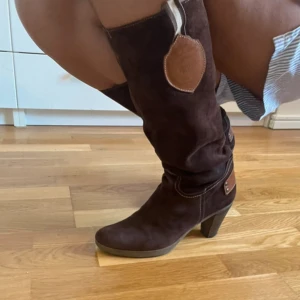 Bruna mockastövlar från Novita - Snygga knähöga stövlar från Novita i mörkbrun mocka med dekorativa sömmar och bruna skinnpatchar. Lätt använda men inte mycket, skriv om frågor! Priset kan såklart diskuteras 💗