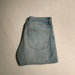 Ljusblå straight jeans från H&M - Säljer ett par ljusblå jeans från H&M i modellen straight regular fit. Klassisk femficksdesign, normal passform och raka ben. Jeansen är tillverkade i jeansmaterial och har en enkel, stilren look som funkar till många olika stilar.