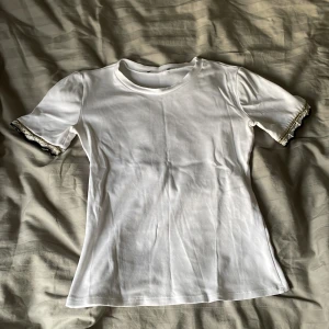 Vit T-shirt från Zara - Vit T-shirt från Zara med jätte fina detaljer på armarna, perfekt till sommaren. Lappen är bortklippt på grund av att den kliade väldigt mycket i nacken.