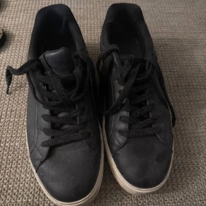 Svarta sneakers från Pull&Bear - Svarta sneakers från Pull&Bear med klassisk design och snörning. Skorna har en vit sula och är tillverkade i syntetmaterial. Perfekta för dig som gillar en enkel och stilren look.