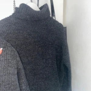 Mörkgrå stickad polotröja H&M - Mysig mörkgrå stickad polotröja från H&M i storlek S. Tröjan har en hög krage och är ribbstickad för extra struktur. Perfekt för kyliga dagar och enkel att styla med jeans eller kjol. Klassisk och tidlös design som funkar året runt.