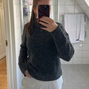 Mörkgrå stickad tröja med rund hals - Stickad tröja från lager 157 i en fin mörkgrå färg. Stilren men kommer tyvärr inte till användning längre. Strl S/M