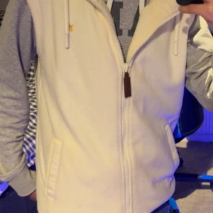 Vit fleeceväst från Pier One - Vit fleeceväst från Pier One. Västen har en liten gul broderad fågel på bröstet som är riktigt fett. Perfekt för hösten och ha till exempel en grå hoodie under. 