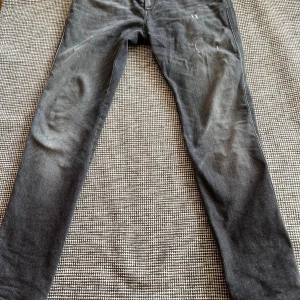 Replay Anbass svarta slim jeans - Snygga svarta Replay Anbass jeans med slim passform. Jeansen har slitna detaljer framtill, klassiska bakfickor och Replay-logga vid fickan. Tillverkade i stretchigt jeansmaterial för en bekväm känsla. Perfekta för dig som gillar en modern och stilren look.