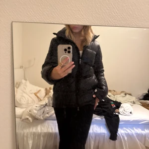 Svart pufferjacka med dragkedja - Säljer en svart pufferjacka med hög krage och dragkedja framtill. Jackan har en klassisk quiltad look och är perfekt för kyliga dagar. Den är långärmad och har en snygg, lite oversized passform. Grym att slänga på sig när det är kallt ute! Ny pris på jackan är runt 2000kr