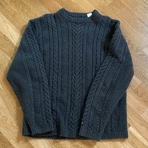 Mörkgrå stickad tröja från Levi's - Säljer en mörkgrå stickad tröja från Levi's i storlek XS. Tröjan har ett klassiskt flätmönster, rund halsringning och långa ärmar. Perfekt för kyliga dagar och enkel att matcha med jeans
