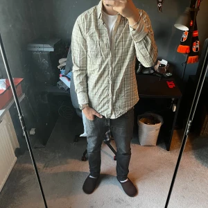 Hugo Boss flanellskjorta - Säljer en snygg rutig skjorta från Hugo Boss i slim fit-modell. Skjortan är i ljusa toner med inslag av blått, beige och grått. Den har långa ärmar, klassisk krage och knäppning framtill. Perfekt för dig som gillar stilrena och bekväma plagg. Skriv för mer bilder