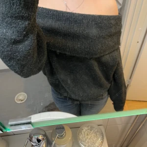 Mörkgrå offshoulder stickad tröja - Mysig mörkgrå stickad tröja med bred offshoulder-krage. Tröjan har lång ärm och en loose passform som ger en avslappnad vibe. Perfekt för kyliga dagar när du vill vara både bekväm och snygg.❤️