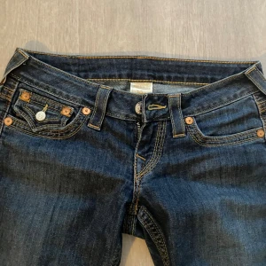 True Religion LOWWAIST jeans blå denim - (Kan sys om till bootcut!🩵)Snygga blå skinny jeans från True Religion med klassiska kontrastsömmar och detaljerade bakfickor med lock och silverfärgade knappar. Jeansen har låg midja och smal passform hela vägen ner. Perfekta för dig som gillar street och premium denim.