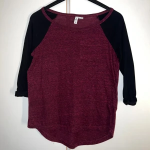 Vinröd och svart tröja från H&M Divided - Vinröd tröja med svarta trekvartsärmar från H&M Divided. Modellen har rund halsringning och en avslappnad passform. Materialet är mjukt och lätt, perfekt för dig som gillar enkel och stilren design. Snygg färgkombination som funkar året runt.