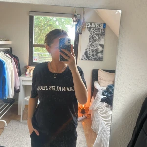 Svart Calvin Klein Jeans t-shirt L - Svart t-shirt från Calvin Klein Jeans i storlek L. Klassisk modell med rund halsringning och vit logga tryckt över bröstet. 