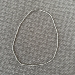Enkelt silverfärgat pärlhalsband - Säljer ett stilrent halsband med små, runda pärlor i silverfärg. Halsbandet är cirka 37 cm långt och har ett klassiskt lås. Perfekt för dig som gillar minimalistiska smycken med en clean vibe. 🩶🩶🤍