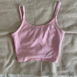 Ljusrosa ribbad linnetopp FB Sister - Supersöt ljusrosa ribbad linnetopp från FB Sister i storlek XS. Toppen har smala axelband och croppad passform, perfekt till sommaren. Mjuk och stretchig i materialet, enkel att matcha med jeans eller kjol.