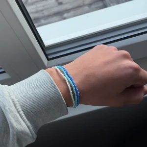 Blått och vitt pärlarmband - Tre tunna armband med små pärlor i blått, ljusblått och vitt. Perfekt för dig som gillar en enkel men färgglad stil. Armbanden är elastiska och sitter snyggt runt handleden. Säljs som set om tre stycken. Snyggt på både tjejer och killar!