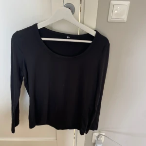 Svart långärmad topp i bomull - Enkel och stilren svart långärmad topp med rund halsringning. Perfekt att matcha med jeans eller kjol för en clean look. Mjuk och skön bomull som känns bra mot huden.