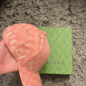 Rosa keps med monogram - Säljer en snygg rosa keps från med klassiskt-monogram över hela kepsen. Kepsen har broderad logga framtill och justerbart spänne bak i beige läder. Perfekt för dig som vill ha en lyxig och trendig accessoar.