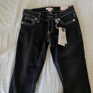Lågmidjade bootcut jeans Tall - Säljer dessa oanvända jeans från gina 14+. Dem är svarta med vita detaljer, lågmidjade och bootcut. Super snygga!! Säljer för jag råka köpa tall, och dem är för långa för mig.