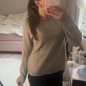 Beige stickad tröja från Vero Moda - Mysig beige stickad tröja från Vero Moda i storlek XS. Tröjan har rund halsringning, långa ärmar och ribbade muddar vid ärmslut och nederkant. Perfekt för lager-på-lager under kyliga dagar.