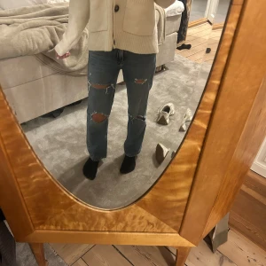 Blå ripped straight jeans - Säljer ett par blå jeans med raka ben och snygga slitningar vid knäna och är i ett lite loose fit. Perfekt för dig som gillar en avslappnad och trendig stil. Färgen är ljusblå. Säljer för de är lite små.
