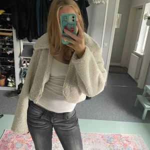 Vit teddyjacka från NA-KD - Säljer en fluffig och croppad teddyjacka från NA-KD i snygg vit färg. Jackan har stora slag, dragkedja framtill och är tillverkad i mjukt teddy-material som håller dig varm. Perfekt för dig som vill ha en trendig och cozy look. Skriv om frågor!! ❤️❤️