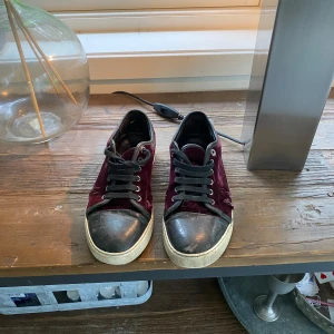 Vinröda sneakers i sammet från Lanvin - Snygga sneakers från Lanvin i vinröd sammet. Skorna är använda men har lite kvar att ge. Storlek 5(motsvarar 40)