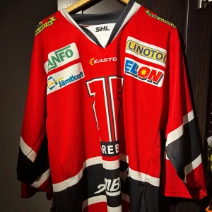 Röd Örebro hockeytröja - Säljer en röd Örebro hockeytröja. Tröjan har svartvita detaljer, Perfekt för dig som älskar hockey.